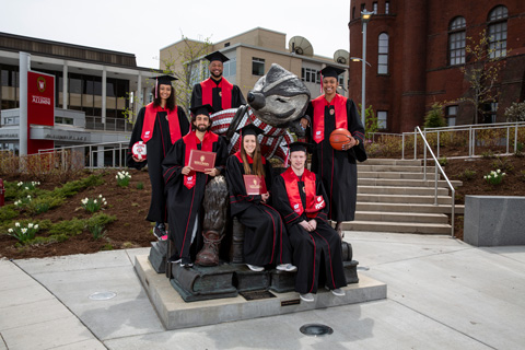 Six Badger student-athletes pose for a picture on the statue of Bucky outside at the Alumni Park.